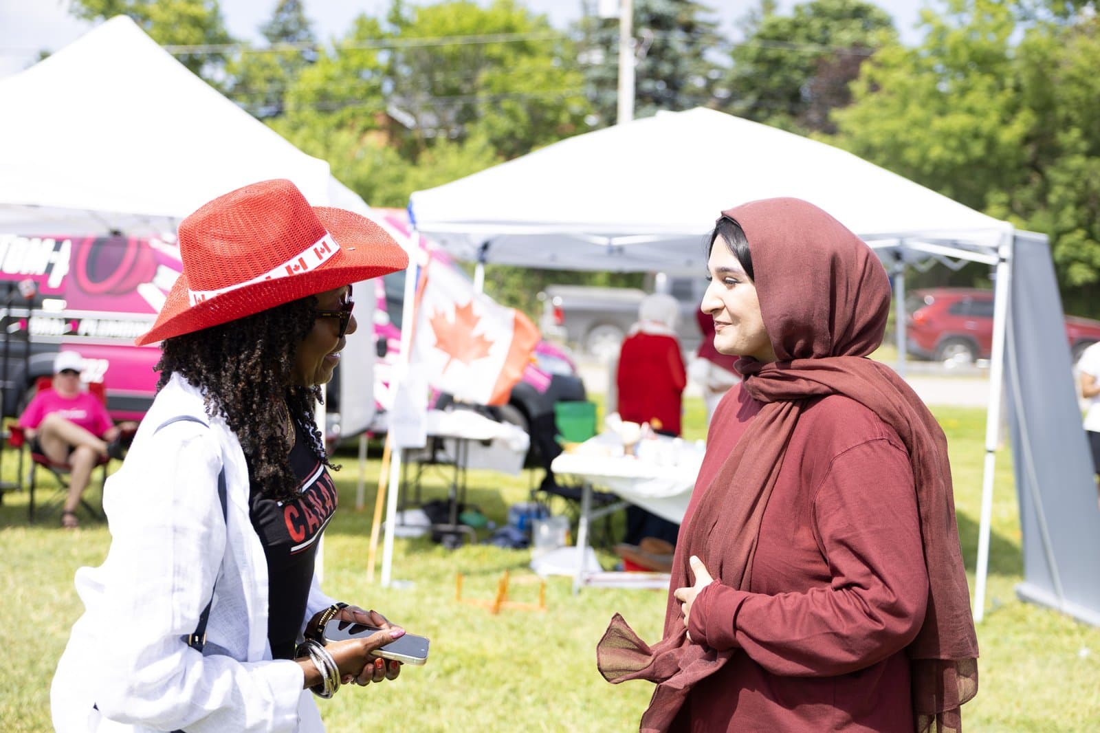 Zainab talking with a resident in Canada Day gear, flag flying behind