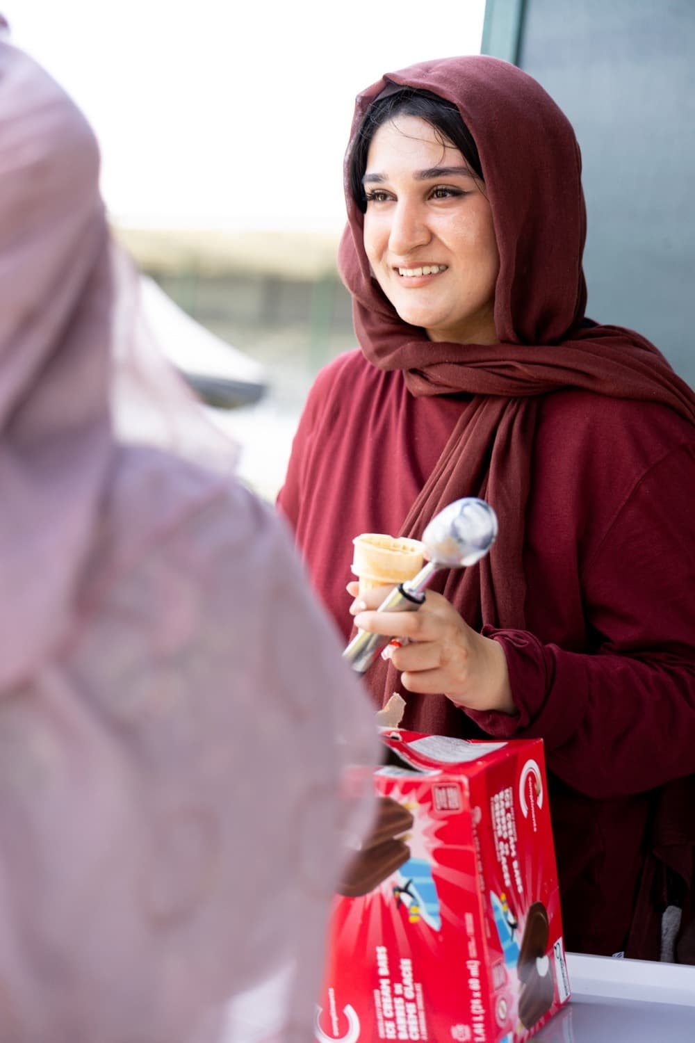 Zainab serving ice cream at a neighbourhood community social